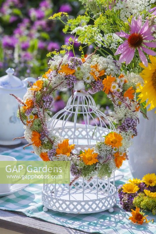 Wreath made of pot marigold, wild carrots, persicaria and tall fleabane hanging from bird cage.