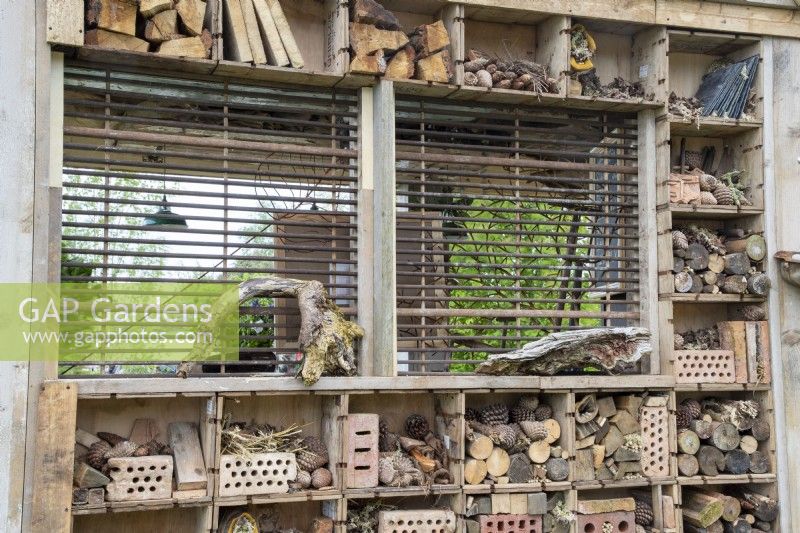 An insect bug hotel made from reclaimed reused salvaged materials and wood off cuts and pine cones for insects habitat