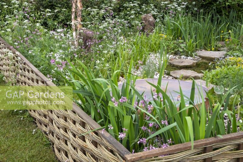 Woven willow fence with a wildflower planted garden and water feature