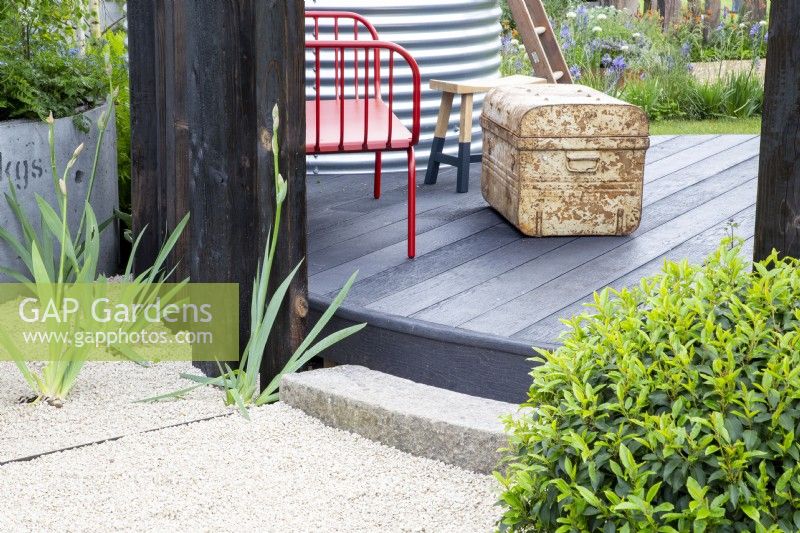 Gravel path with curved stone step up to circular composite board raised deck
