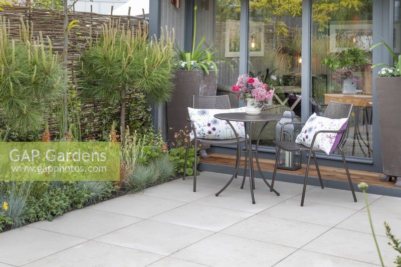 Garden building and seating area surrounded by planting in 'The Home Solutions by John Lewis Garden' at BBC Gardeners World Live 2019