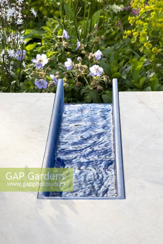 A modern contemporary water rill made from recycled plastics set in polished stone 