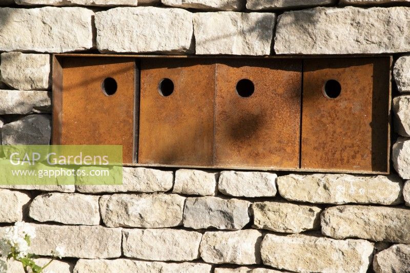 Corten steel nesting boxes to attract endangered tree sparrows who nest in groups set into a drystone wall