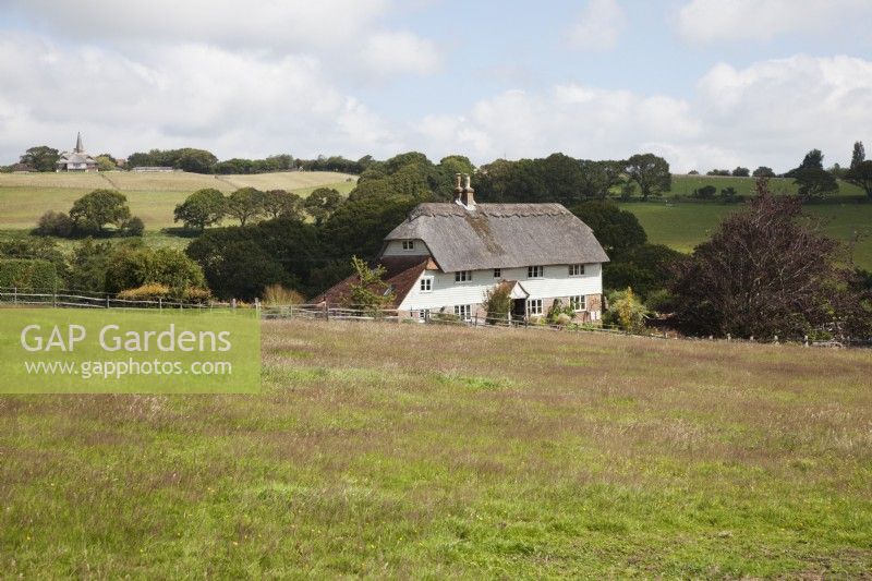 Farmhouse surounded by fields with post and rail fencing, countryside views and church views .