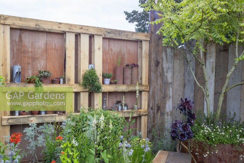 Garden fence made from salvaged reclaimed timber scaffolding boards and wooden pallets used as shelves and drought tolerant planting - Punk Rockery Garden 