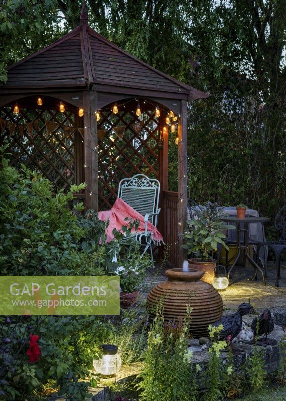 Garden gazebo with water feature and solar lights in the evening - August