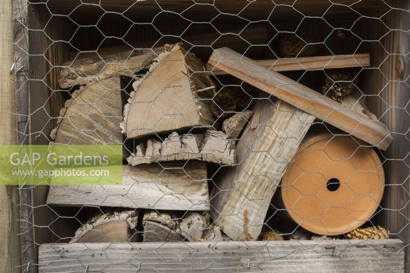 Bug hotel made from cut logs, tree bark and flowerpot for insects to hide and hibernate in.