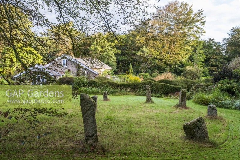 Circular granite standing Stone Circle in large grassed area in autumn garden