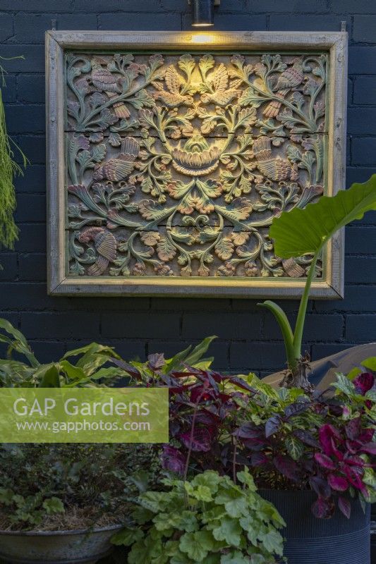 Carved and painted Indonesian wall panel light with a single downlight.