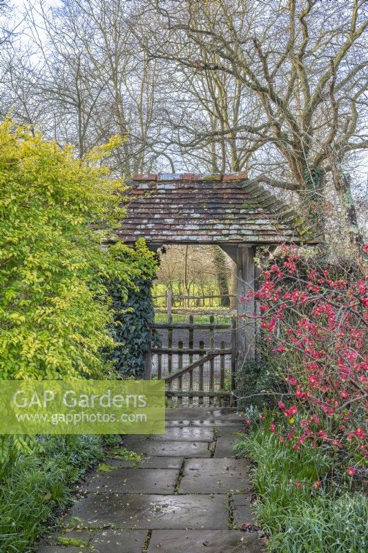 View through a covered lych gate garden entrance in early Spring - February