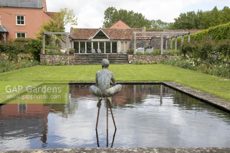 Naked male sculpture squatting above a pond in the bronze garden at Yeo Valley Organic Garden, May