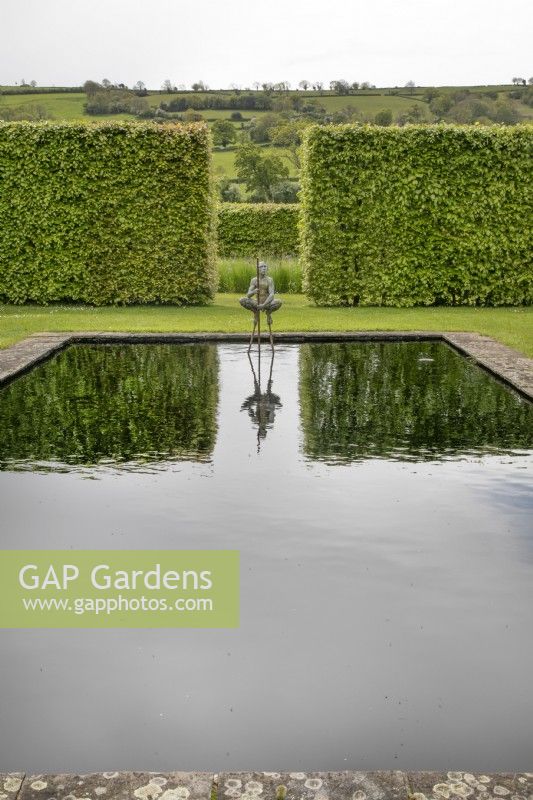 Naked male sculpture squatting above a reflecting pool in the bronze garden at Yeo Valley Organic Garden, May