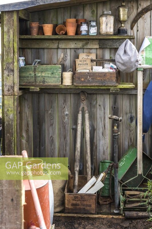 Inside garden shed with old garden tools, clay pots and vintage wooden boxes with gardening books