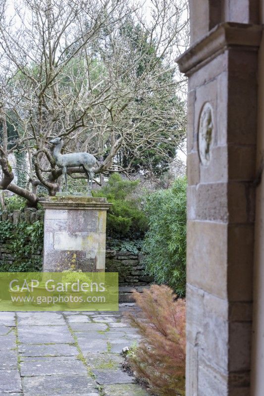 Sculpture of a deer on a plinth seen from inside the Loggia at Iford Manor in January