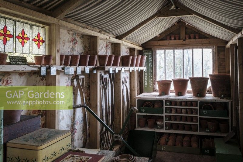 Decorated potting shed filled with old tools, pots, gardening books and guides