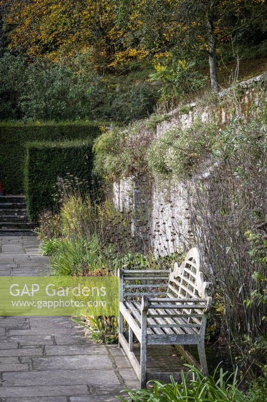 Lutyens style garden bench in peaceful walled garden, autumn