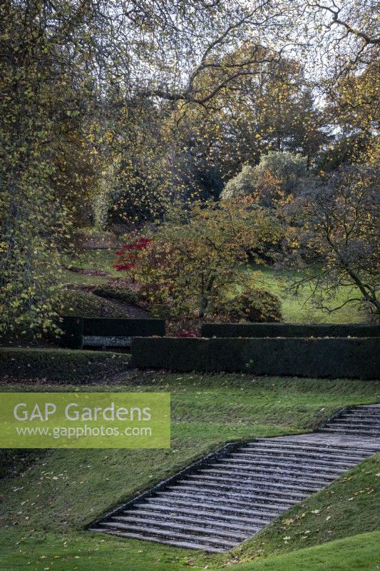 View across the 'tilt yard' with grass terraces and a flight of stone steps in autumn at Dartington Hall, Devon