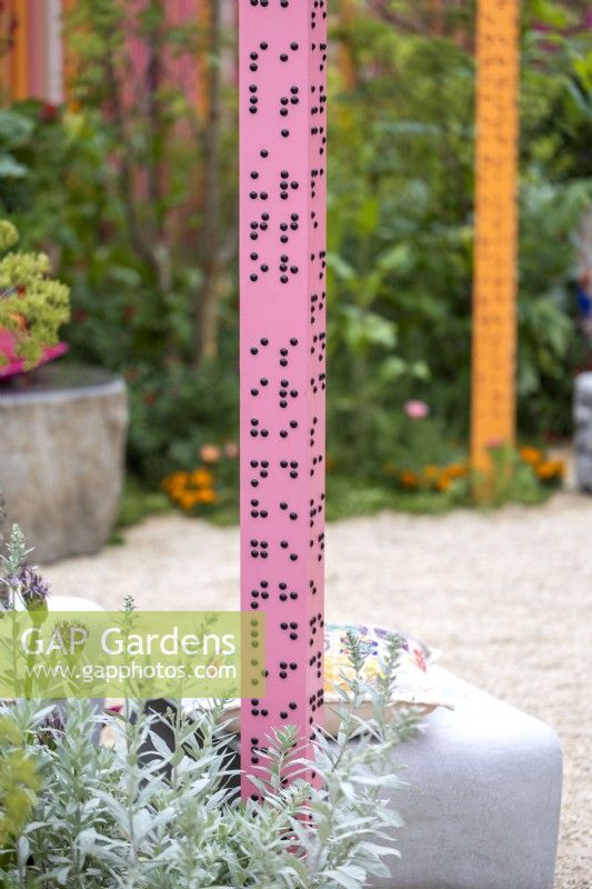 Pink post with sentences in braille in The RHS and Eastern Eye Garden of Unity. Designer: Manoj Malde, May