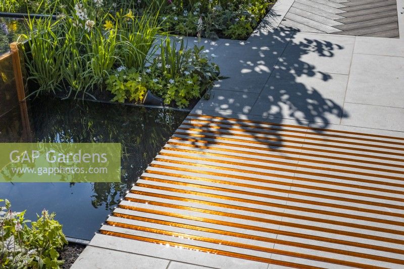 Tiled boardwalk with a fluted copper grooves with water from the water feature located above