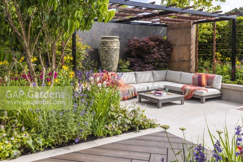 Contemporary garden with secluded seating area, steel pergola, walking board and large ceramic vase. Border planted with Acer palmatum, Heptacodium and coloured perenials. Designer: Kevin Dennis, Bord Bia Bloom 2023