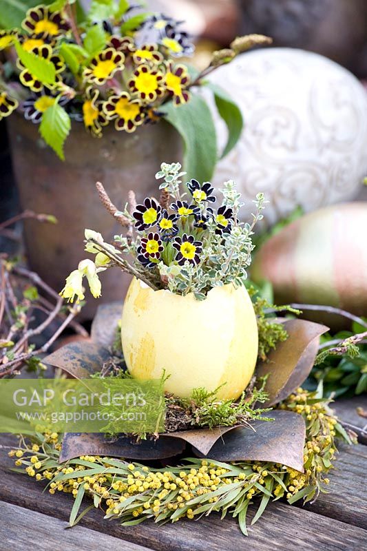 Floristically decorated egg with Primula victoriana, thyme and hazel 
