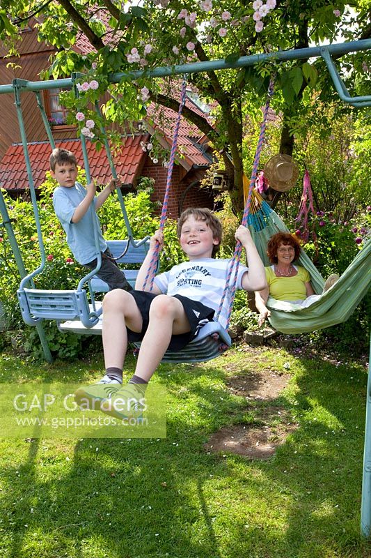 Children playing on swing, mother watching from hammock 