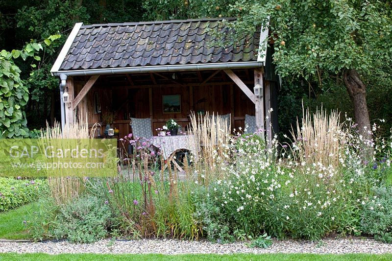 Covered seating area, in front of it reed grass and Calamagrostis acutiflora Overdam, Gaura lindheimeri Whirling Butterflies 