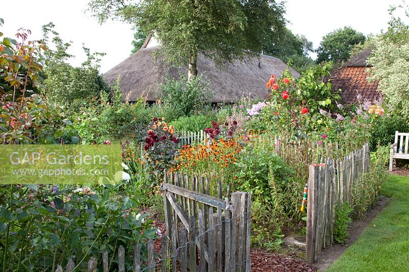Country garden with thatched house in the background 