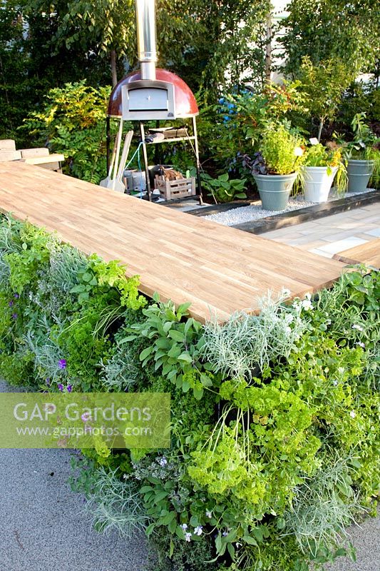 Vegetable garden with outdoor kitchen, worktop on the sides planted vertically with herbs 