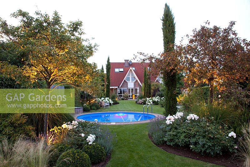 Illuminated garden with pool, serviceberry and crabapple, Amelanchier, Malus 