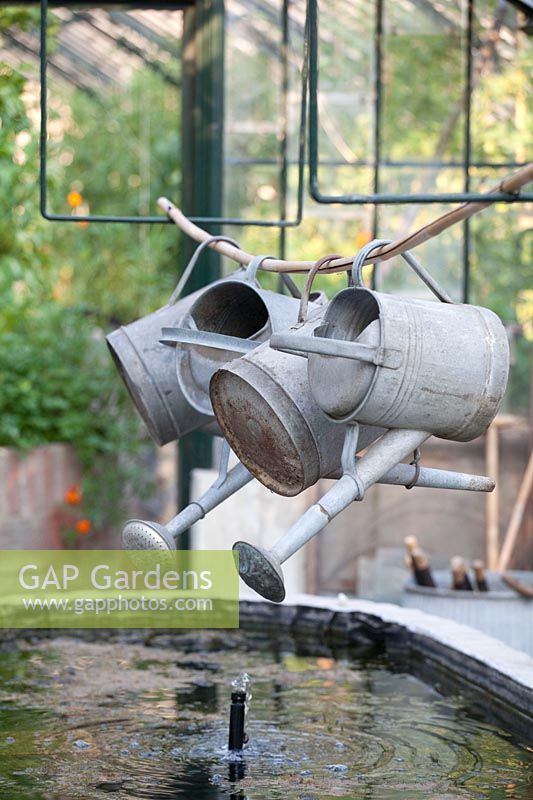 Watering cans on a bamboo stick in the greenhouse 