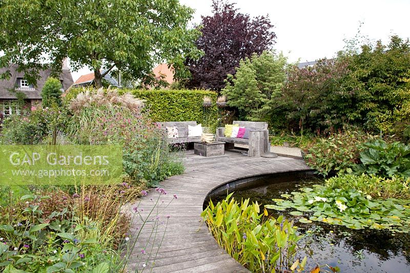 Seating area by the pond with curved wooden walkway 