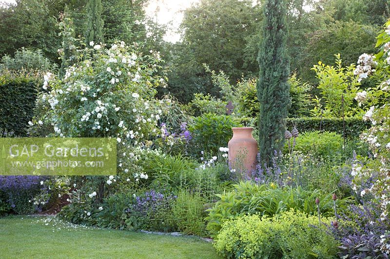 Perennial bed with roses and amphora 