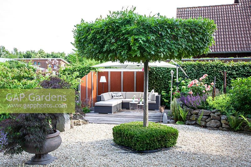 Modern garden with lounge furniture and hanging umbrella 
