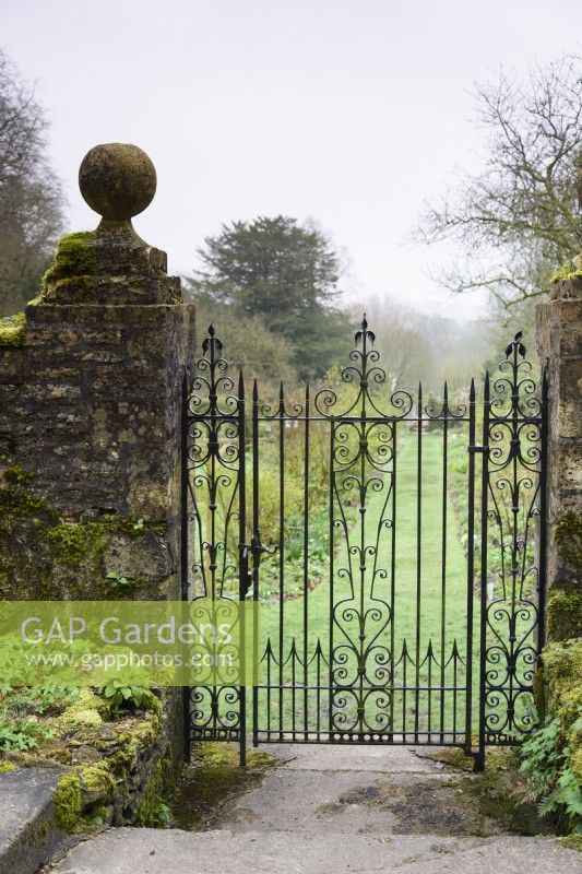 Mossy gateposts framing a metal gate in the walled garden at Cerney House in March