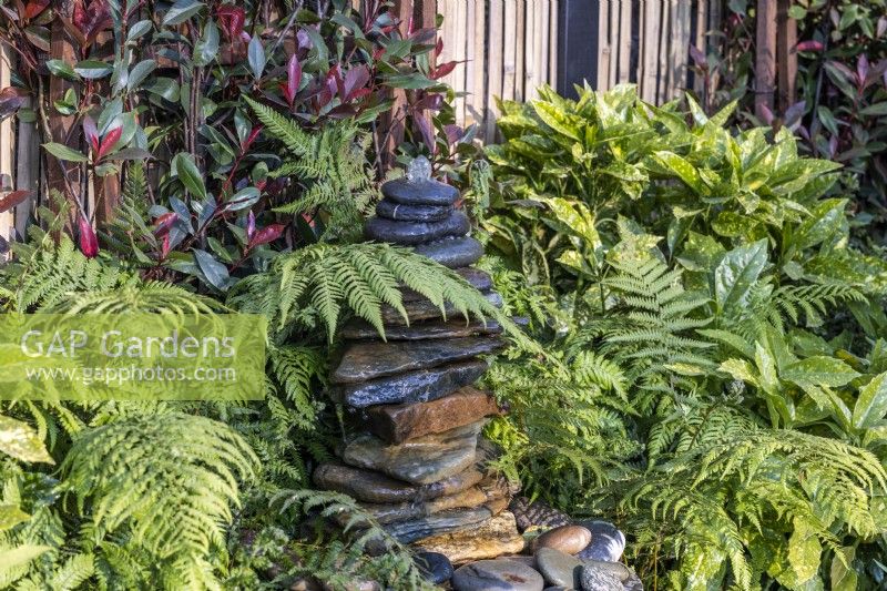 Slate water fountain surrounded by fern leaves