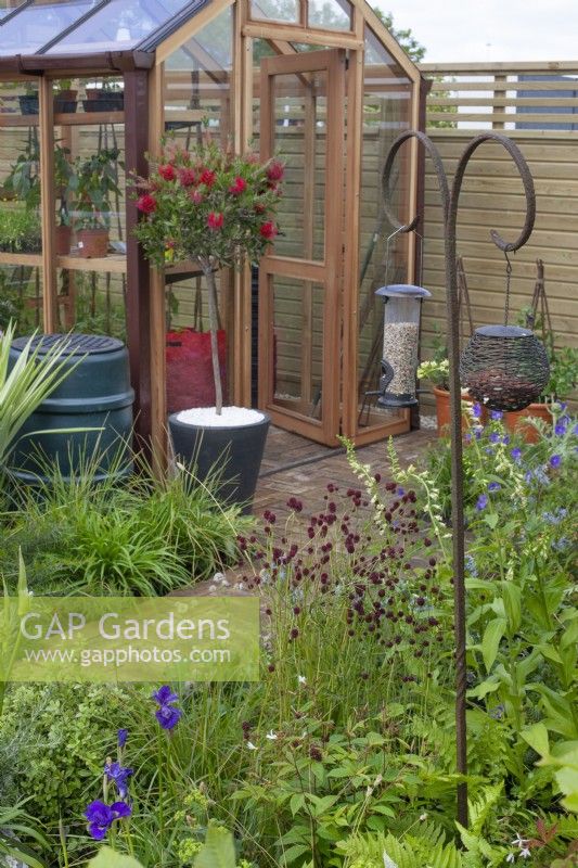 Bird feeding station amongst border of perennials in the 'Greener Pastures' garden at BBC Gardener's World Live 2015, June