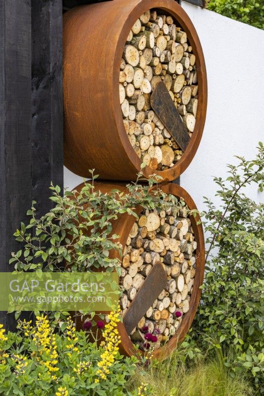 Round insect hotels made of wood and rusty rings in an urban front garden. Designer: Nicola Haines