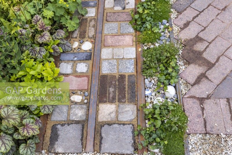 Front garden - detail of driveway made with reclaimed cobbles, tiles, bricks, rusted rails, stones. The planting include: Sagina sabulata, Hedera helix, Heuchera and Pachysandra. Designer: Nicola Haines, Citroen Power of One at Bord Bia Bloom Dublin 2023