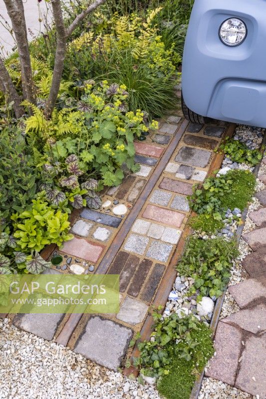 Front garden - detail of driveway made with reclaimed cobbles, tiles, bricks, rusted rails, stones with low level green foliage. Designer: Nicola Haines, Citroen Power of One at Bord Bia Bloom Dublin 2023