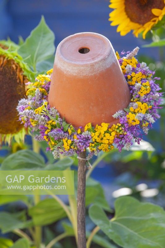 Upturned flower pot with a wreath of summer flowers including Allium, Agastache and Tanacetum vulgare.