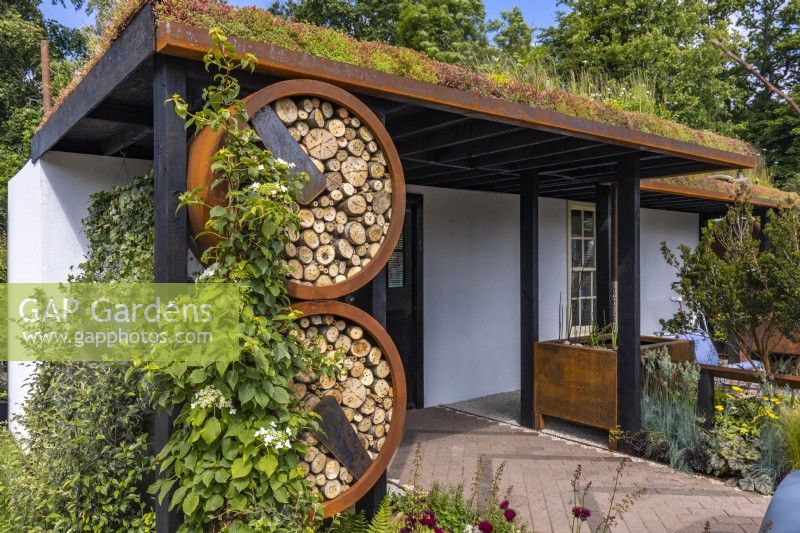 Covered entrance to the house with a Sedum roof and insect houses in urban front garden. Designer: Nicola Haines Garden: Citroen Power of One at Bord Bia Bloom Dublin 2023
