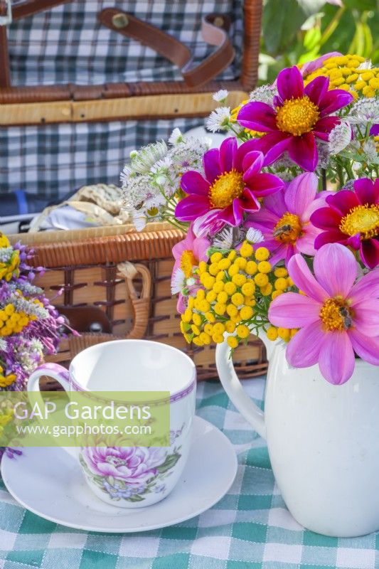 Tea cup and a summer bouquet containing Dahlia, Tanacetum vulgare and Astrantia in a white jug.