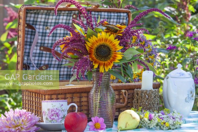 Summer bouquet with sunflowers and Amaranthus caudatus on the table set for picnic.