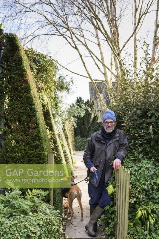 Older man with his dog leaning on his garden gate in January