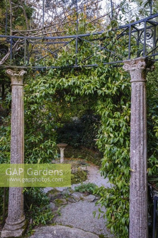 Two stone pillars, part of a Classical style temple looking back in to a lush semi tropical garden