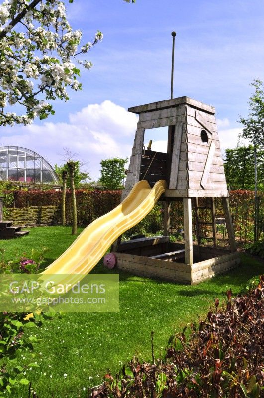 Mobile children's play feature with slide in a spring garden.