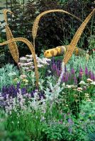 Ornaments in herbaceous purple border. Carved caterpillar and woven leaf sculptures
