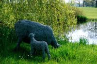 Sheep and lamb sculpted in chicken wire by pond at Old Place Farm in Kent