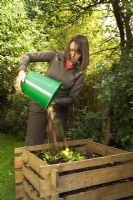 Woman emptying bucket on compost heap